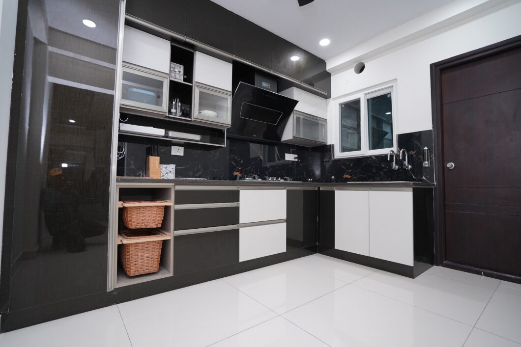 A black and white kitchen with white cabinets designed by Dream Modular at Honer Vivantis - Tellapur - Hyderabad