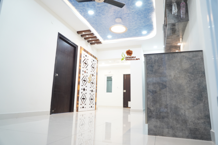 A hallway with a navy blue sky false ceiling fan and white walls with pooja rooms designed by an interior design company in Hyderabad, offering a 10-year warranty.
