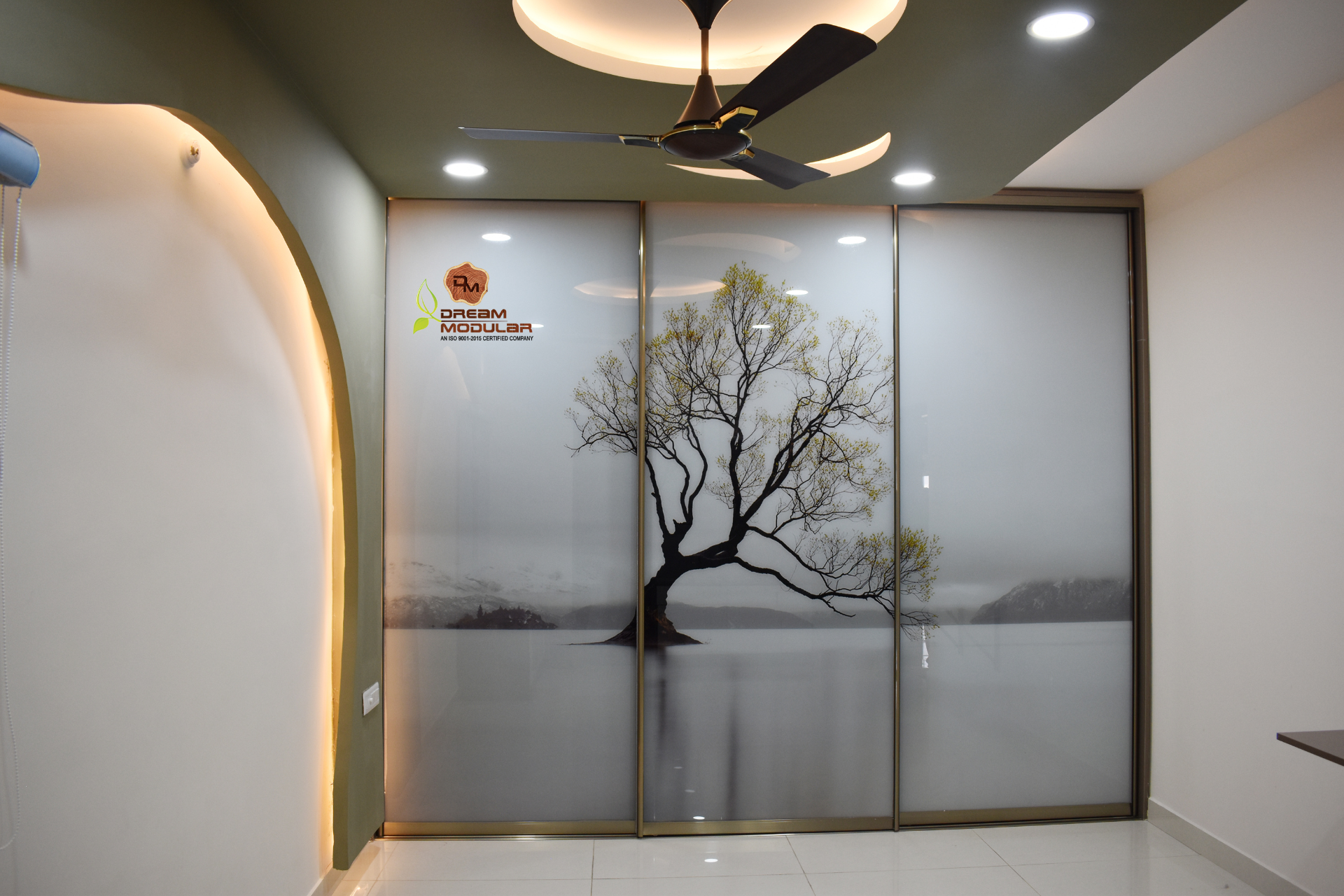 A bedroom with a sliding glass door wardrobe with a coated tree image and modern interior design.