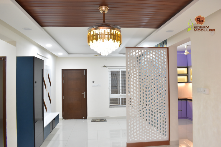 An elegant hallway in a home with a stunning chandelier, Partition. TV Unit, False Ceiling designed by interior designers for their Dream Modular projects.