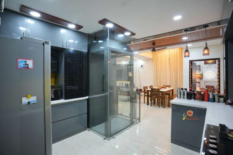 Modern kitchen interior with dining area visible through glass partition.